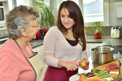 caregiver assisting senior woman in cooking