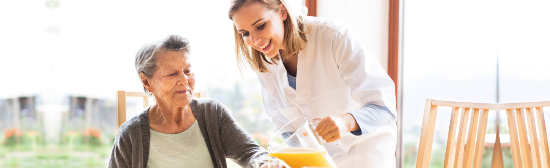 caregiver assisting the senior woman in her meal